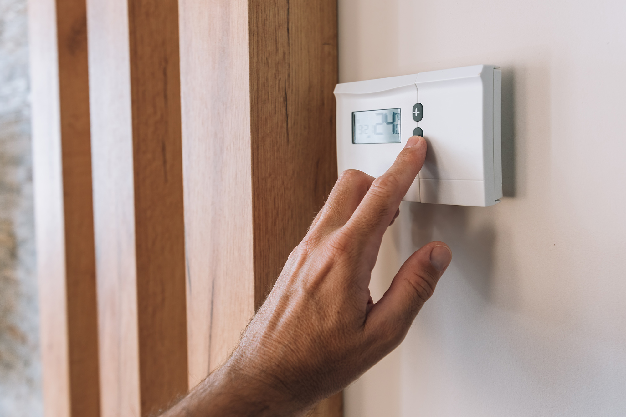 Male hand pushing the button of home heating and cooling system
